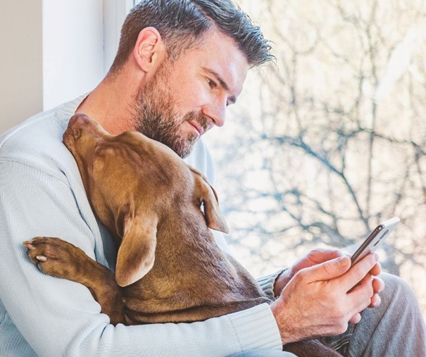 Un éducateur canin avec son chien consulte sa réservation sur téléphone